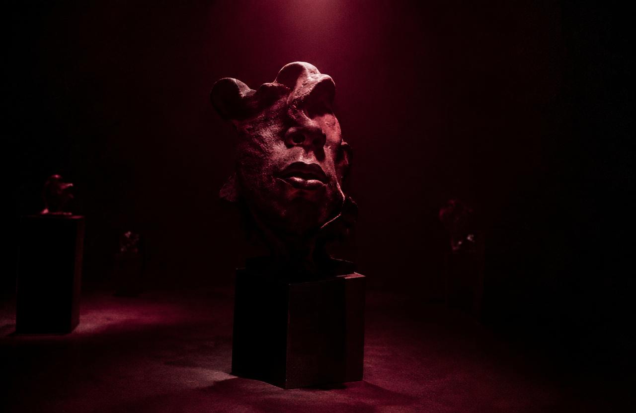 An abstract face emerging from deep red shadows and textured brushwork