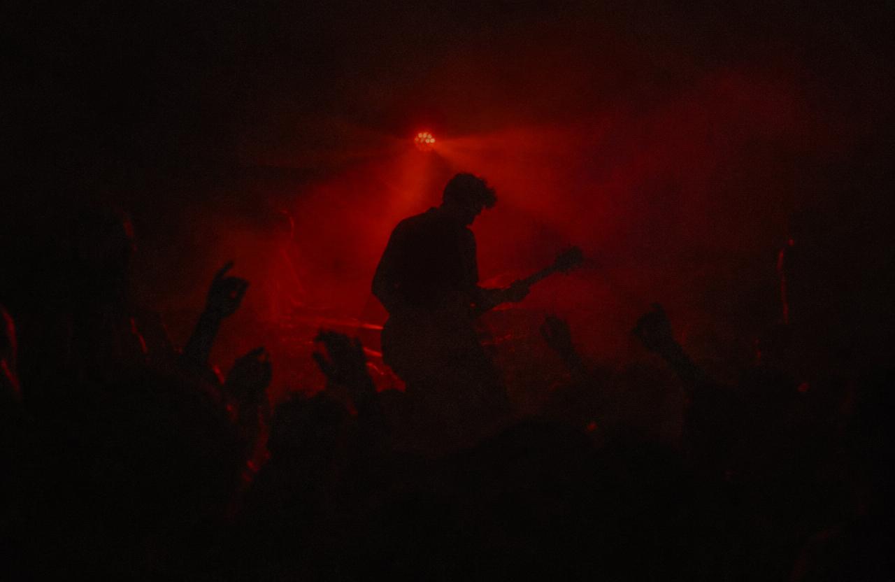 A musician performing through red haze at an underground concert